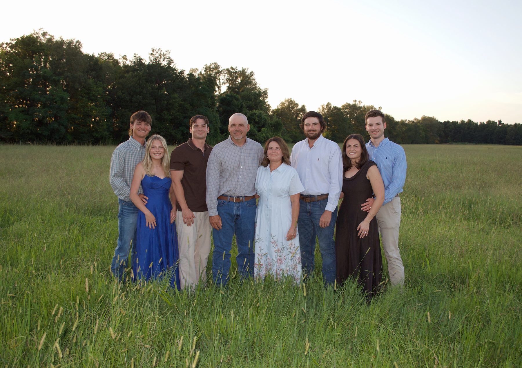 The Miller family standing together in a Baskin pasture at golden evening light